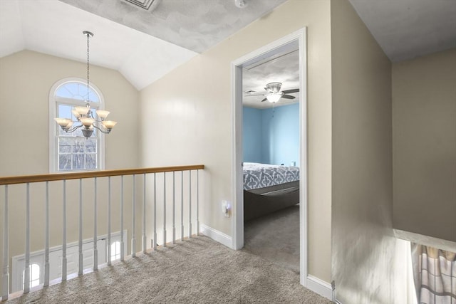 hall with an inviting chandelier, vaulted ceiling, and carpet