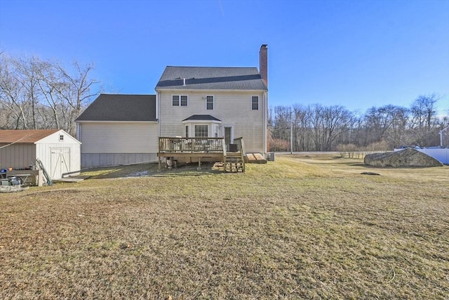 back of property featuring a shed, a lawn, and a deck