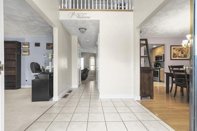 hallway featuring a chandelier and light tile patterned floors