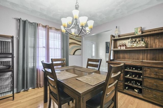 dining room featuring an inviting chandelier, indoor bar, and light hardwood / wood-style flooring