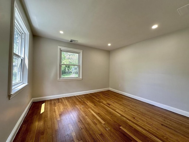 empty room with dark wood-style floors, baseboards, and recessed lighting