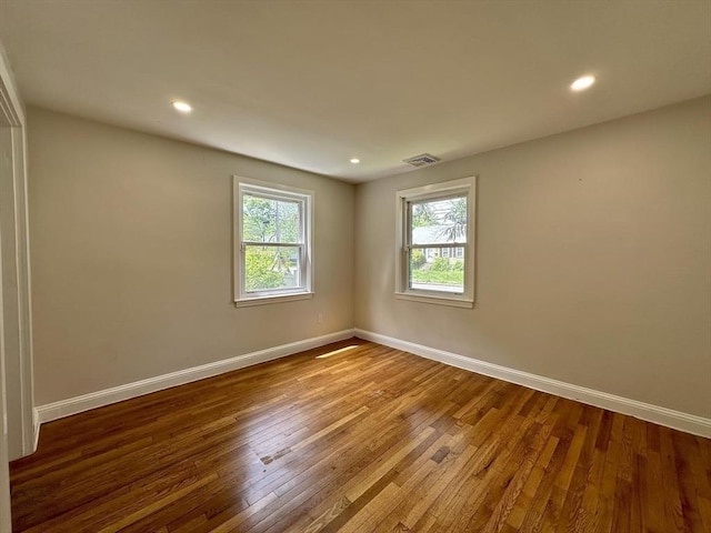 unfurnished room with wood finished floors, baseboards, and recessed lighting