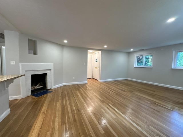 unfurnished living room with wood finished floors, baseboards, a fireplace, and recessed lighting