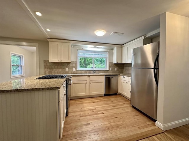 kitchen with appliances with stainless steel finishes, a sink, plenty of natural light, light wood finished floors, and recessed lighting