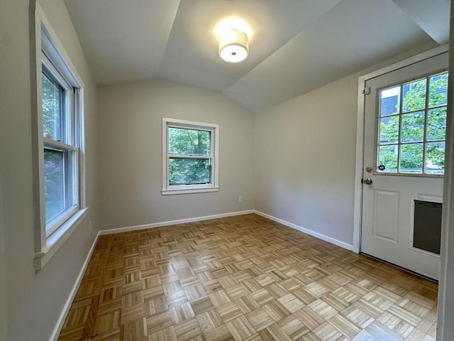 empty room featuring vaulted ceiling and baseboards