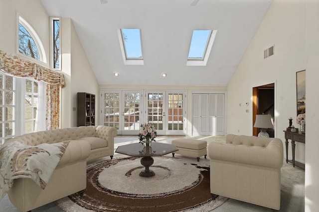 living room with high vaulted ceiling, a skylight, and visible vents