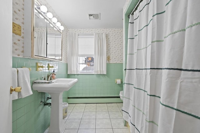 full bathroom with wallpapered walls, visible vents, wainscoting, a baseboard radiator, and tile patterned floors