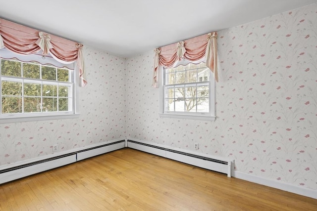 spare room featuring baseboards, light wood-style floors, baseboard heating, and wallpapered walls