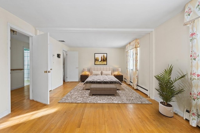 unfurnished bedroom featuring a baseboard heating unit, visible vents, and wood finished floors