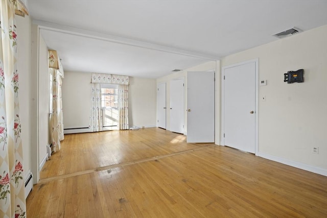 empty room with a baseboard radiator, visible vents, light wood-style flooring, and baseboards