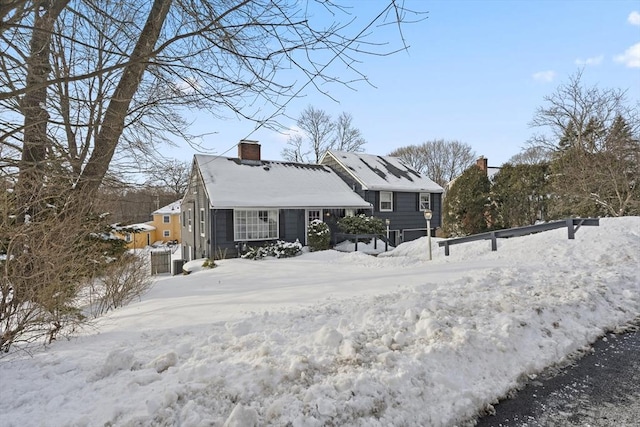 snow covered rear of property featuring a chimney