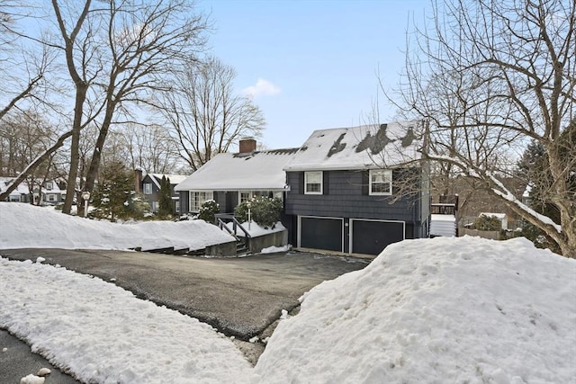 view of front facade featuring a garage, driveway, and a chimney