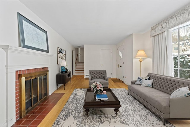 living area featuring dark wood-style floors, a brick fireplace, a baseboard heating unit, and stairway