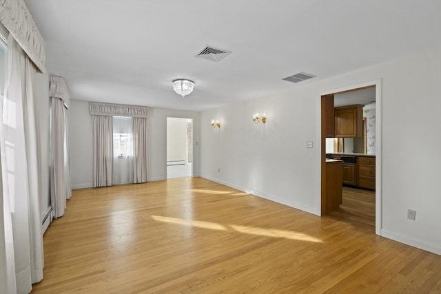 unfurnished room with light wood finished floors, baseboards, visible vents, and baseboard heating