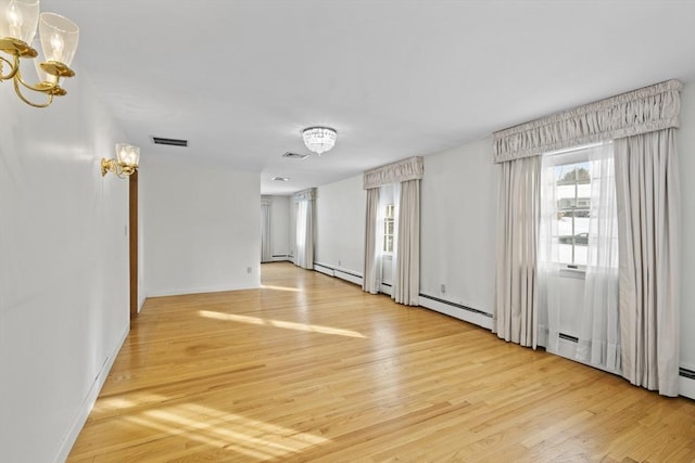 empty room featuring a baseboard radiator, visible vents, light wood-style flooring, and an inviting chandelier