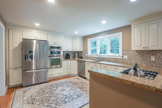 5 Fox Run Rd, Topsfield, MA 01983 - kitchen featuring appliances with stainless steel finishes, light stone countertops, tasteful backsplash, light wood-style floors, and a peninsula
