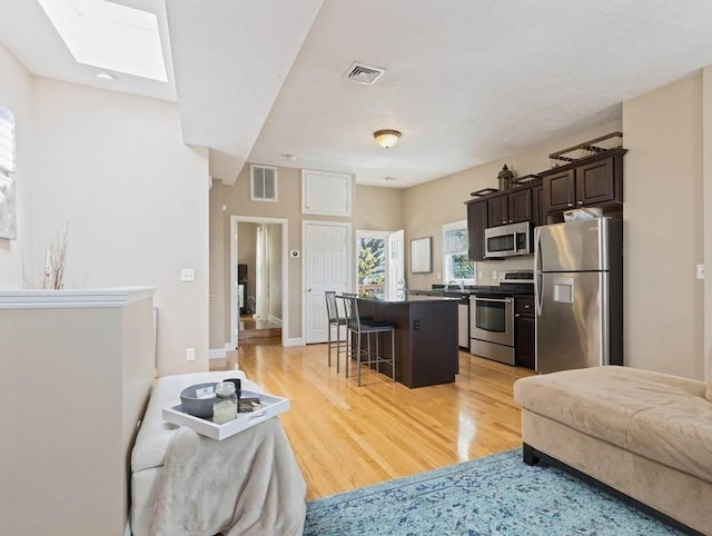 living room featuring light hardwood / wood-style floors and a skylight