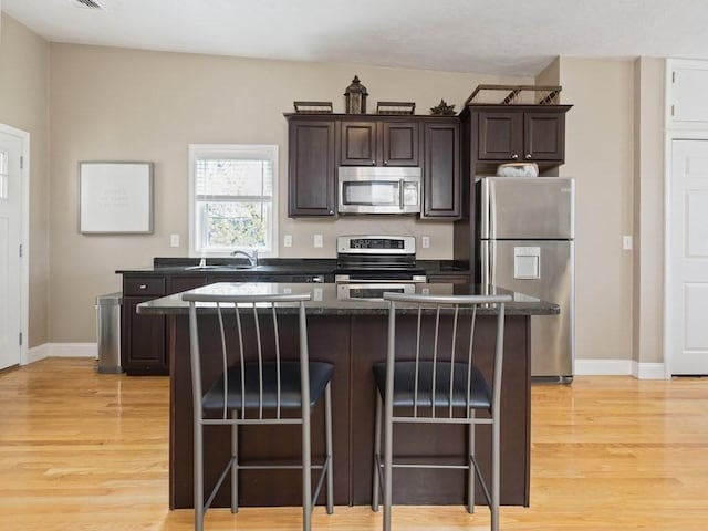 kitchen with a kitchen breakfast bar, appliances with stainless steel finishes, a center island, and dark brown cabinets