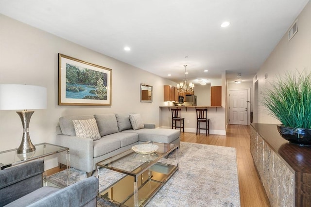 living room with visible vents, recessed lighting, light wood-style floors, an inviting chandelier, and baseboards