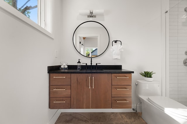 bathroom featuring a tile shower, plenty of natural light, vanity, and toilet