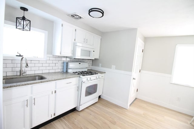 kitchen featuring sink, white appliances, decorative backsplash, white cabinets, and decorative light fixtures