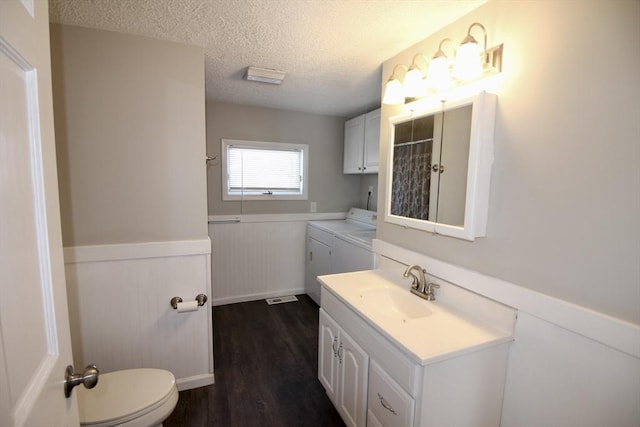 bathroom featuring separate washer and dryer, hardwood / wood-style flooring, vanity, toilet, and a textured ceiling