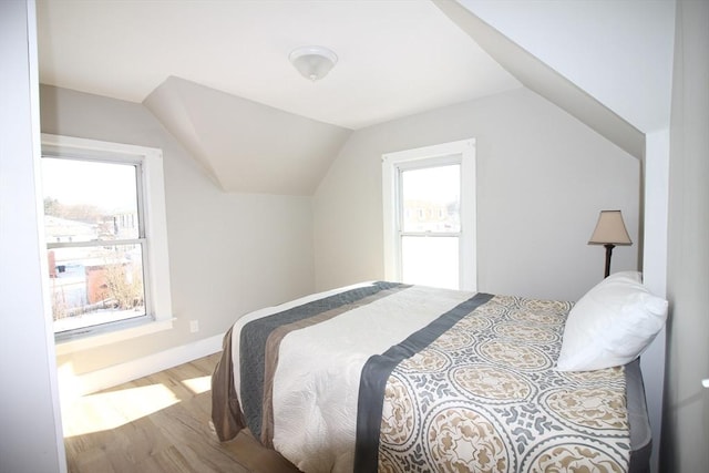 bedroom with multiple windows, hardwood / wood-style floors, and lofted ceiling