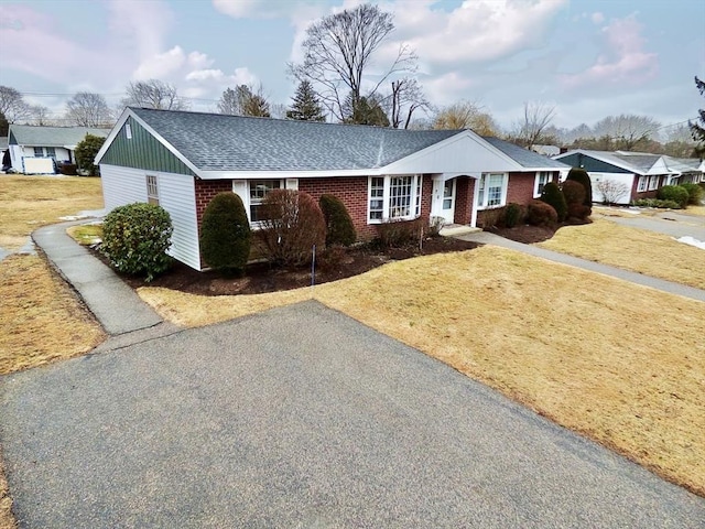 ranch-style house with brick siding, a front yard, and roof with shingles