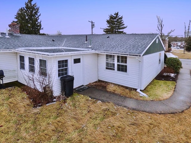 back of property with a chimney and a shingled roof