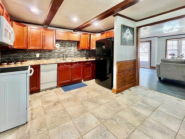 kitchen with white appliances, beam ceiling, a sink, wainscoting, and tasteful backsplash