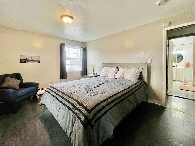 bedroom featuring ensuite bath, dark wood-type flooring, baseboards, and baseboard heating