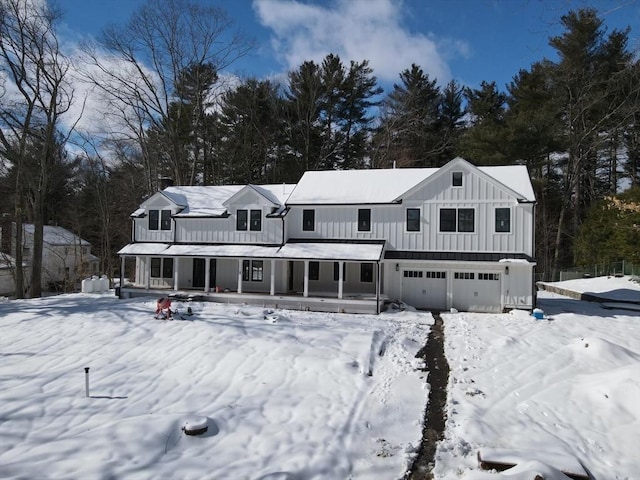 snow covered back of property featuring a garage, board and batten siding, and a porch