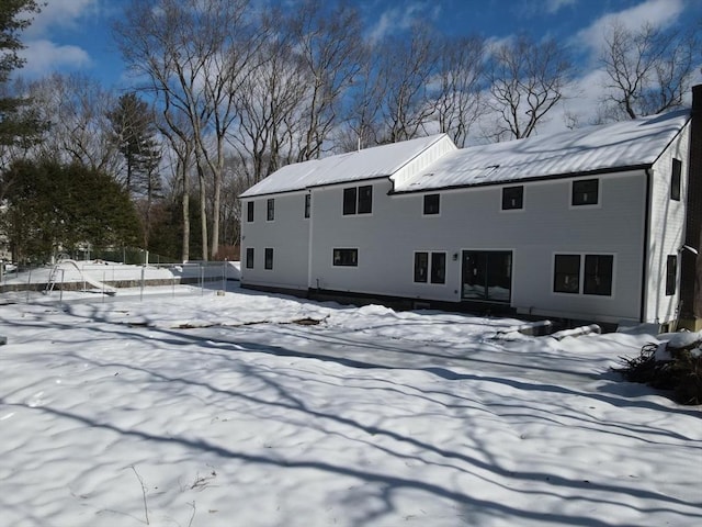 snow covered rear of property with a chimney