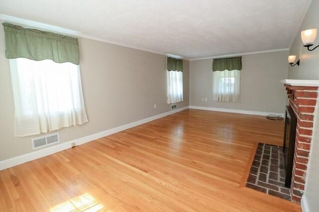 53 Perkins St, Stoneham, MA 02180 - unfurnished living room featuring a brick fireplace, light wood finished floors, and ornamental molding