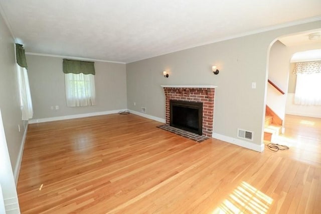 53 Perkins St, Stoneham, MA 02180 - unfurnished living room with light wood-type flooring, healthy amount of natural light, a fireplace, stairway, and ornamental molding