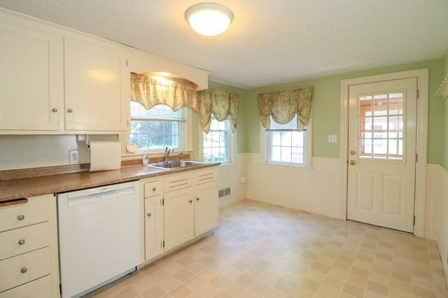 53 Perkins St, Stoneham, MA 02180 - kitchen with white dishwasher, a wainscoted wall, white cabinets, and light floors
