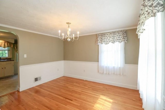 53 Perkins St, Stoneham, MA 02180 - spare room with light wood-style flooring, arched walkways, a chandelier, and ornamental molding