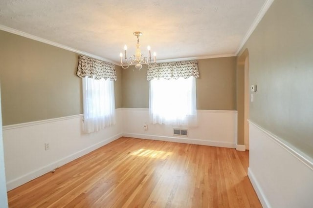 53 Perkins St, Stoneham, MA 02180 - spare room with a chandelier, light wood-style flooring, crown molding, and arched walkways