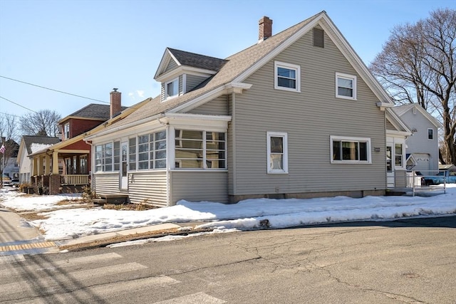 view of snow covered exterior with a chimney and a sunroom