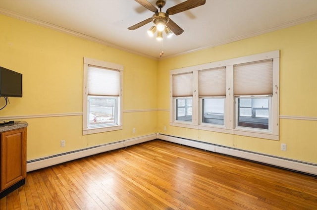 spare room with light wood-style floors, a healthy amount of sunlight, ornamental molding, and ceiling fan