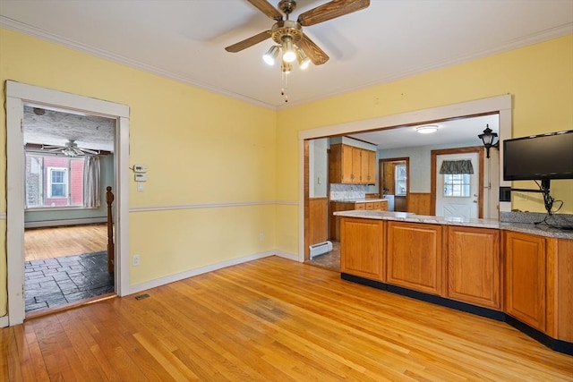 kitchen with brown cabinets, crown molding, a baseboard radiator, a baseboard heating unit, and light wood-type flooring