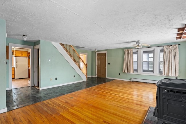 unfurnished living room with hardwood / wood-style flooring, baseboards, stairs, and a baseboard heating unit