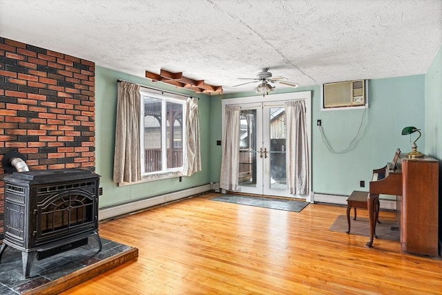 entryway with hardwood / wood-style floors, a baseboard radiator, a wall unit AC, and a wood stove