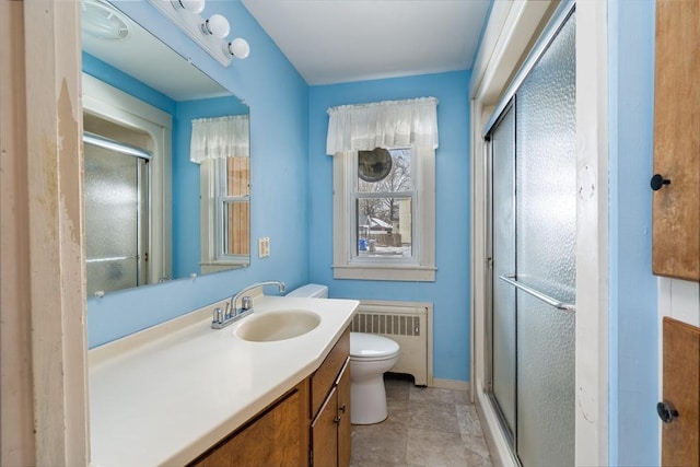 bathroom featuring toilet, vanity, baseboards, radiator, and a stall shower