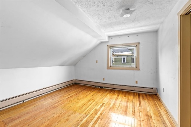 bonus room featuring a baseboard heating unit, lofted ceiling, a textured ceiling, and light wood finished floors