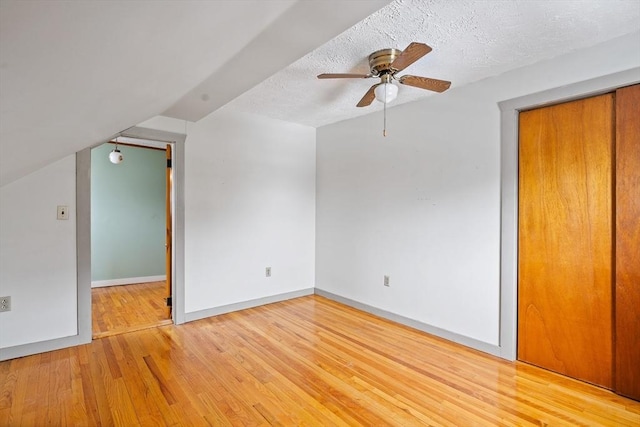 interior space with baseboards, lofted ceiling, ceiling fan, wood finished floors, and a textured ceiling