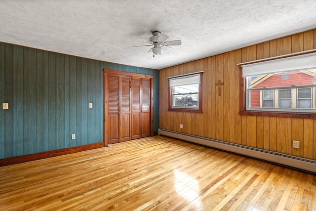 unfurnished bedroom featuring a textured ceiling, ceiling fan, hardwood / wood-style floors, and a baseboard radiator