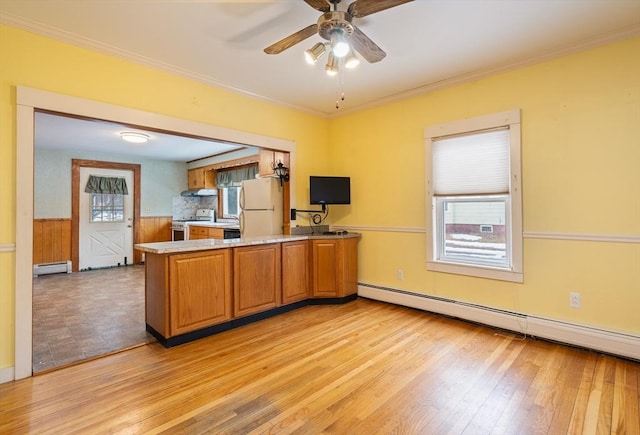 kitchen with a peninsula, a baseboard heating unit, range with gas stovetop, and freestanding refrigerator