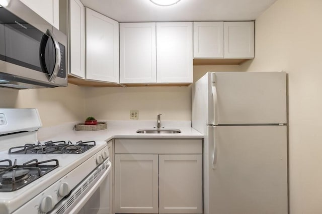 kitchen with a sink, white cabinets, white appliances, and light countertops