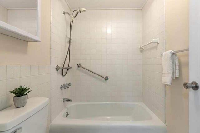 bathroom featuring tile walls, washtub / shower combination, and toilet